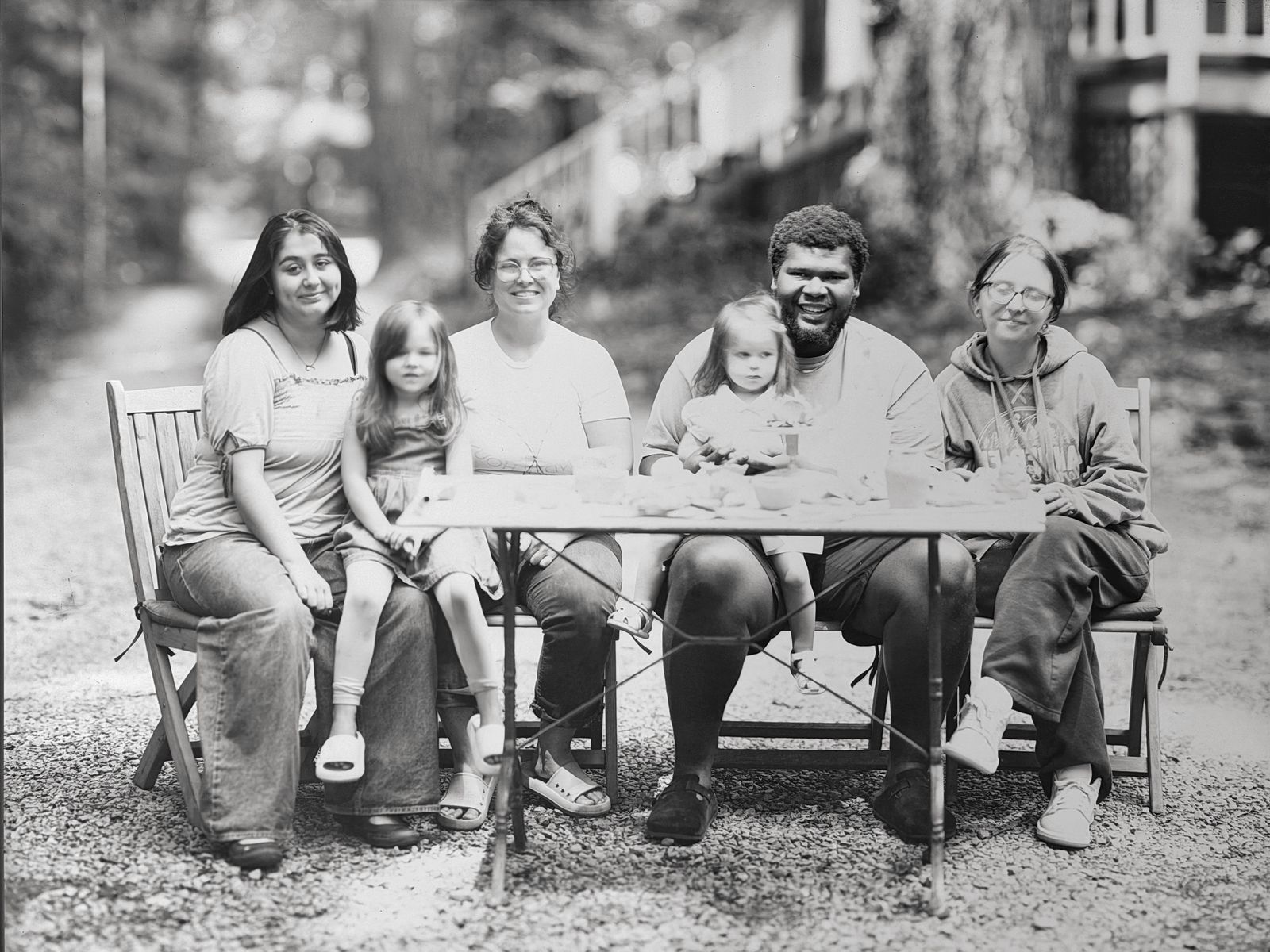 A large group portrait of six people seated around a table outdoors, made with the Giant Camera.